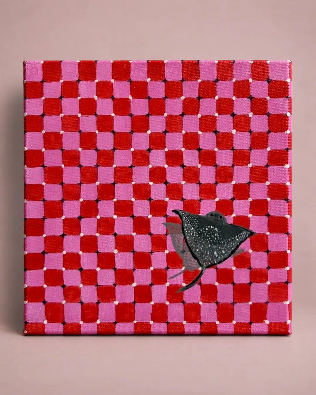 Gingham Sea: a painting of a spotted ray gliding across a hand-painted pink and red checked pattern, photographed against a soft blush backdrop.